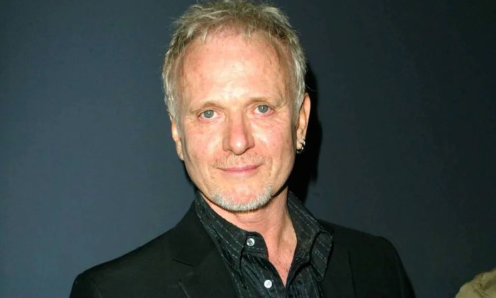 A man with short, light hair and an earring smiles slightly-anthony geary net worth