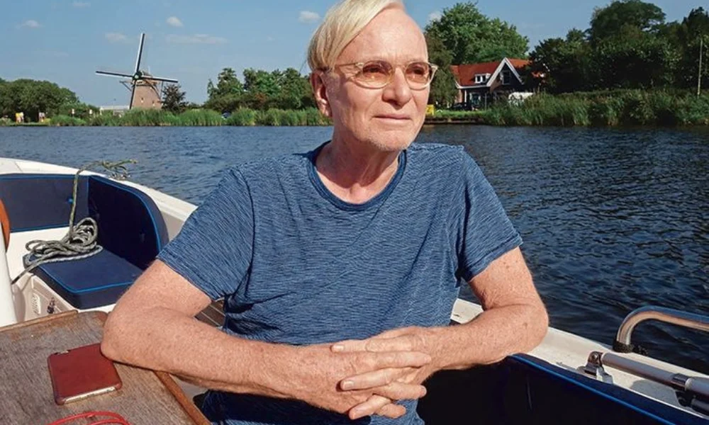 An elderly person with glasses sits on a boat