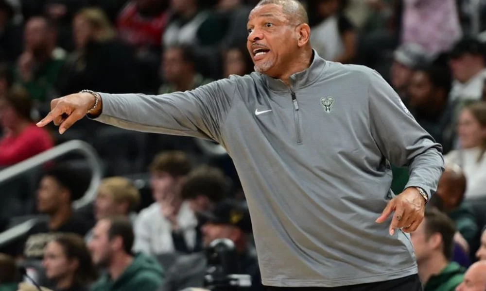 A man in a gray athletic jacket -doc rivers net worth