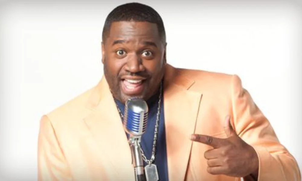 A man in a peach blazer enthusiastically smiles