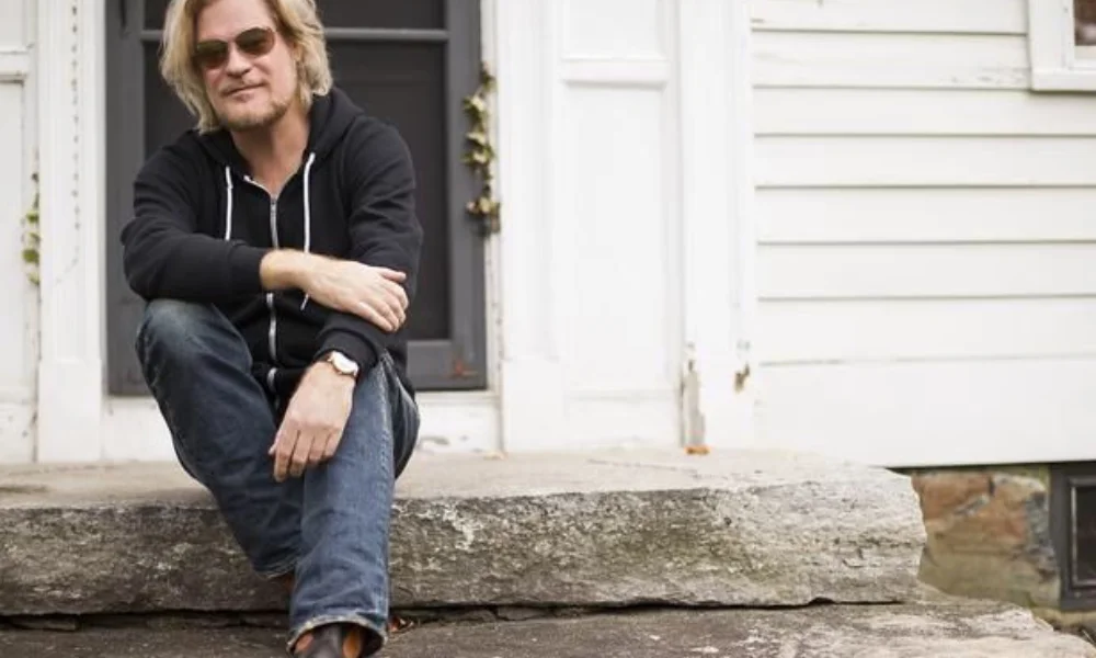 Man with sunglasses and casual attire sits on stone steps