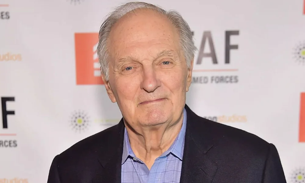 Elderly man with gray hair wearing a blue shirt and dark blazer