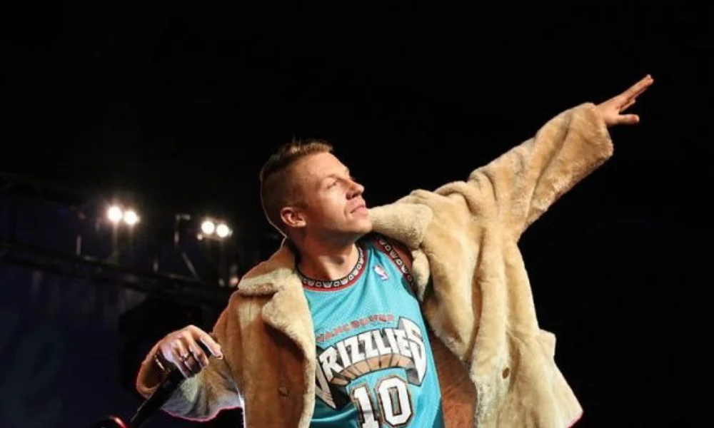 Person in a tan fur coat over a teal Grizzlies jersey-macklemore net worth