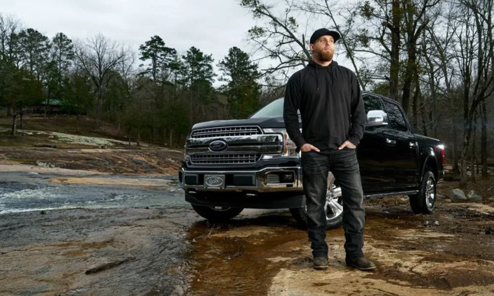 A man in a black cap and jacket stands confidently-brantley gilbert net worth