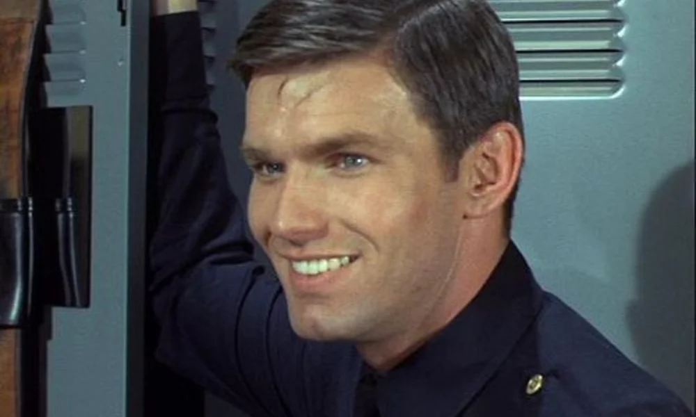 Smiling man in a navy blue uniform stands in front of a locker-kent mccord net worth