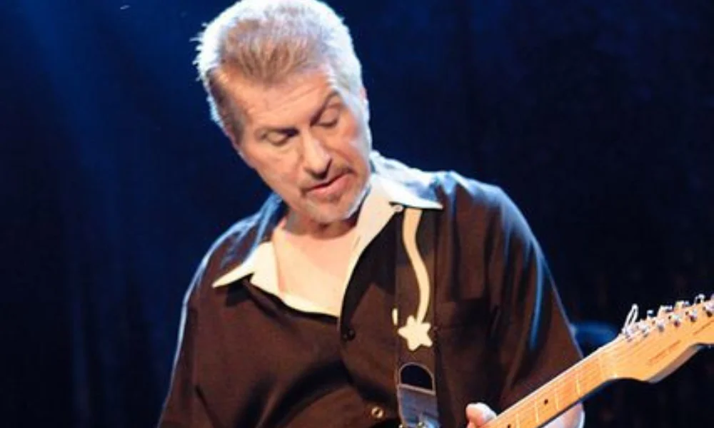 Man playing an electric guitar on stage-johnny rivers net worth