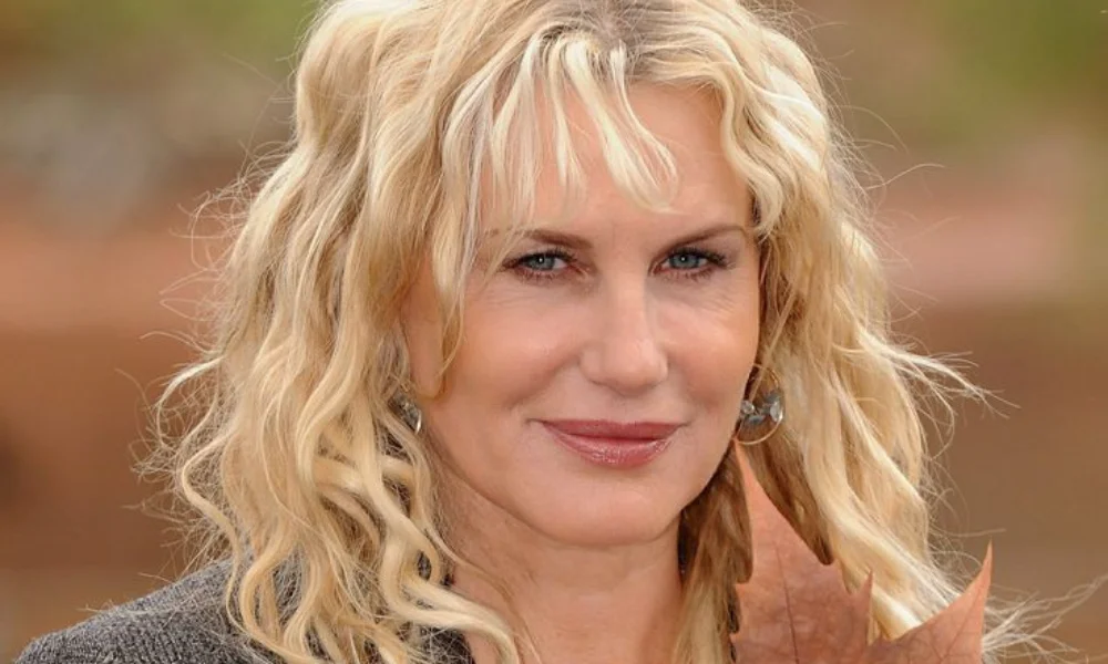 holds a brown autumn leaf beside her face-daryl hannah net worth