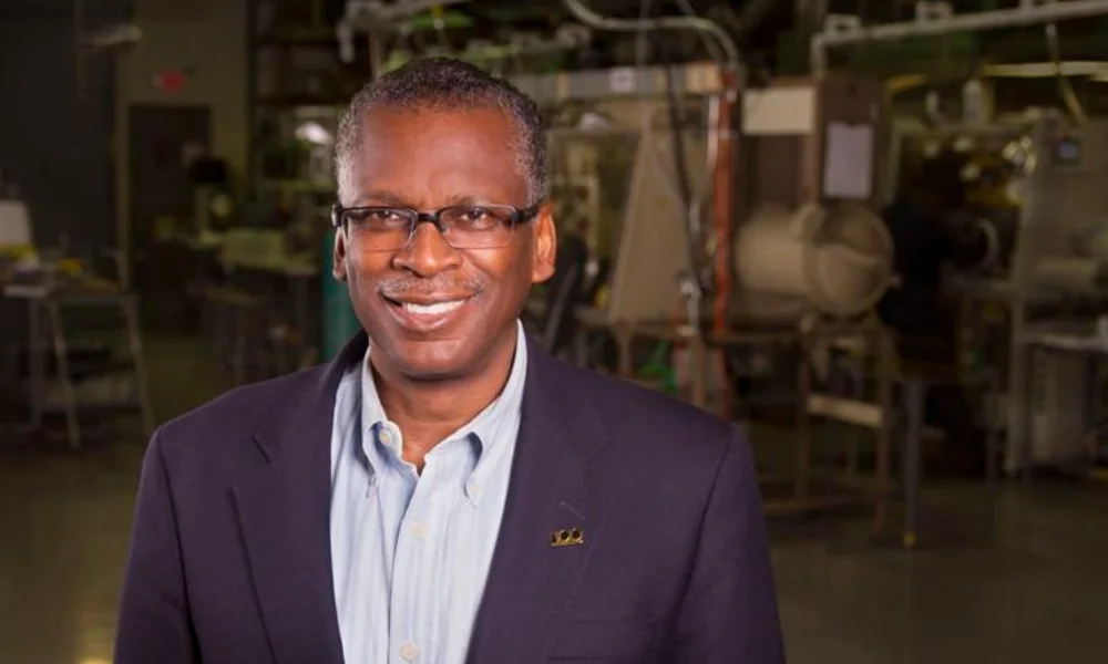 A man in glasses and a blue blazer smiles warmly
