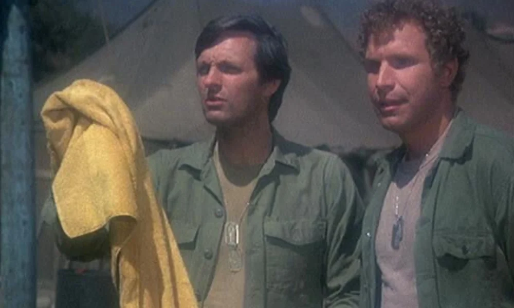 Two men stand outdoors, looking intently ahead-net worth of alan alda