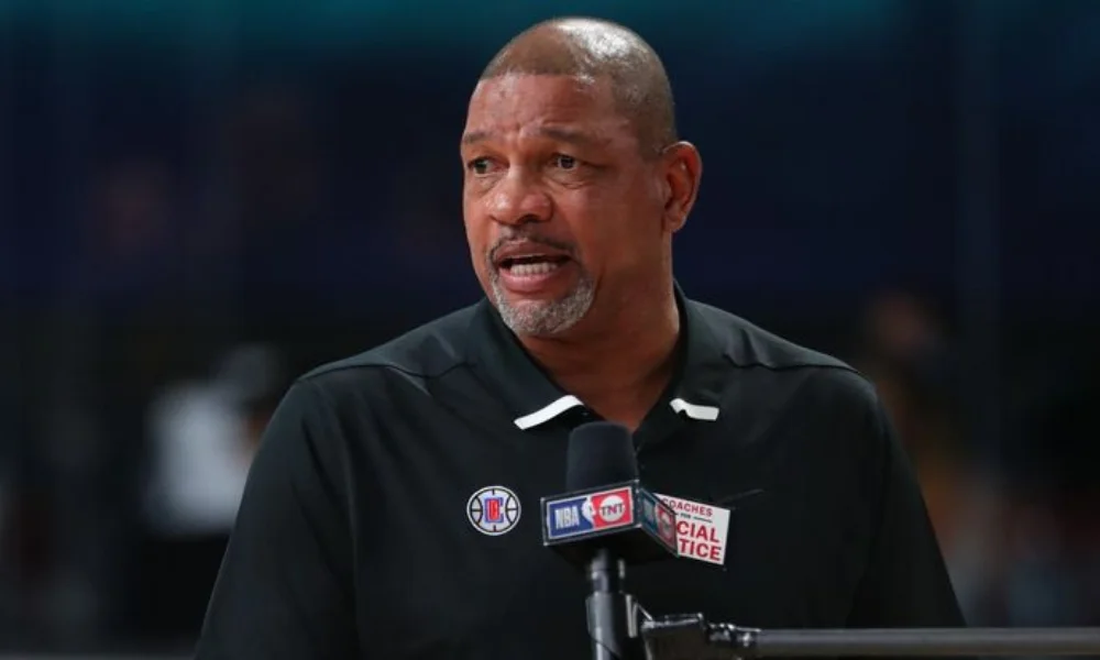 A man in a black shirt with NBA logos speaks passionately-doc rivers net worth