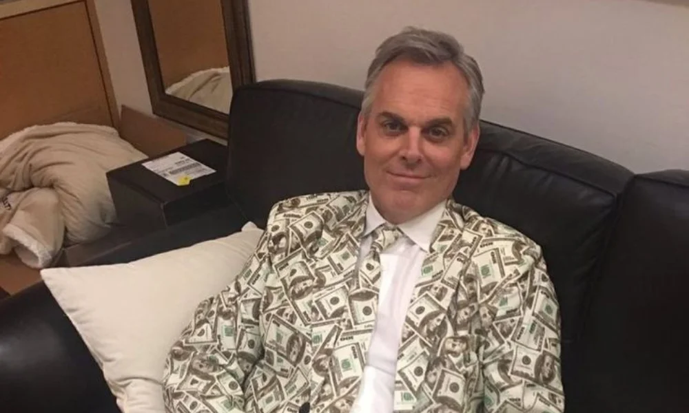 A man with gray hair sits on a black couch-colin cowherd net worth