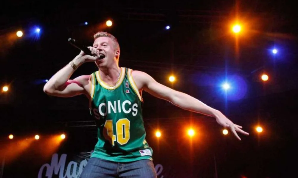 A performer energetically sings into a microphone on stage