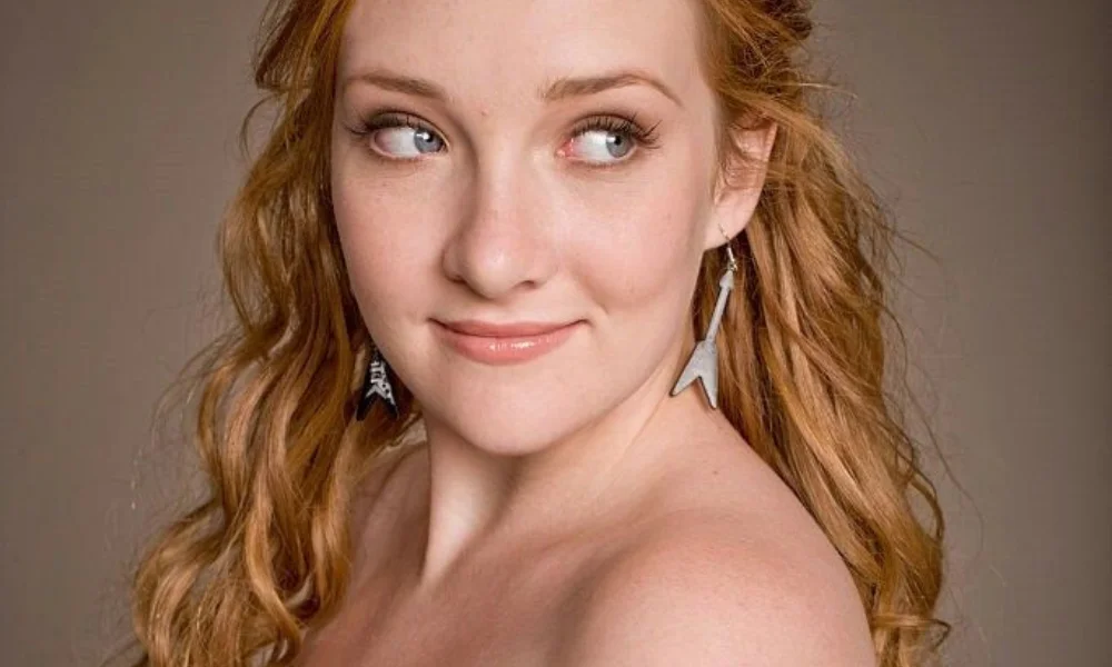 Young woman with red wavy hair smiles slightly-scarlett pomers net worth