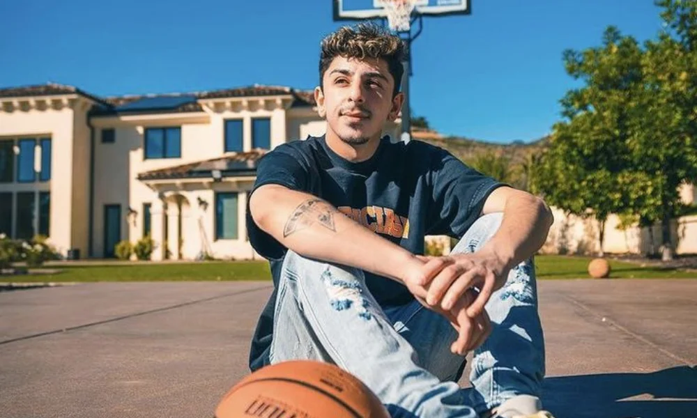 A young man sits on a sunlit basketball court