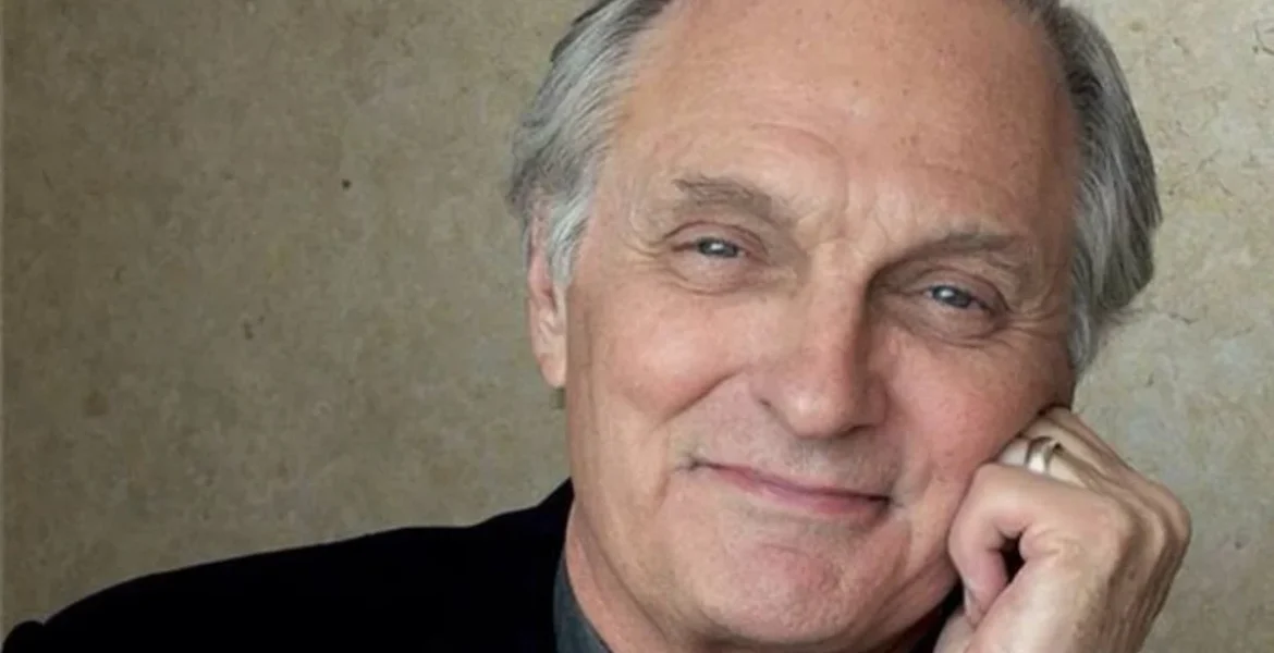Elderly man with gray hair smiles gently, resting his chin on his hand