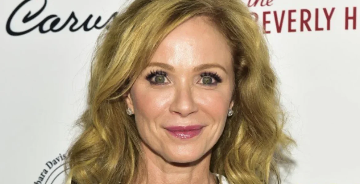 A woman with wavy, shoulder-length blonde hair smiles at the camera