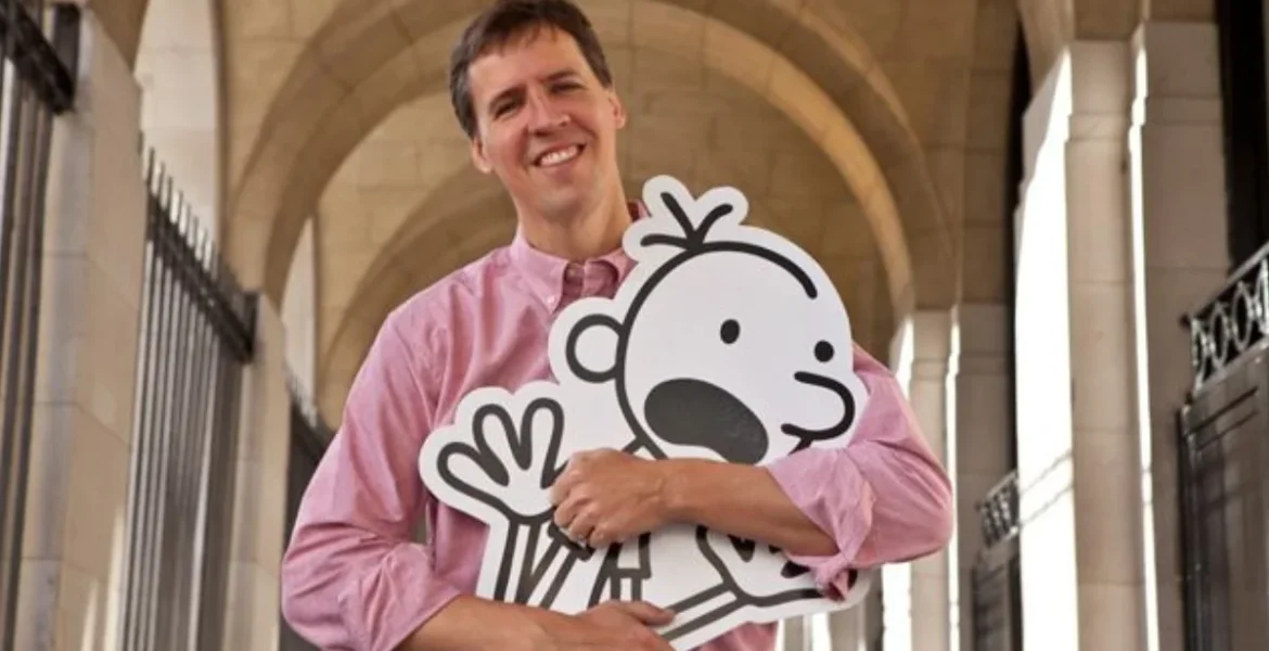 A person in a pink shirt smiles while holding a large cartoon character