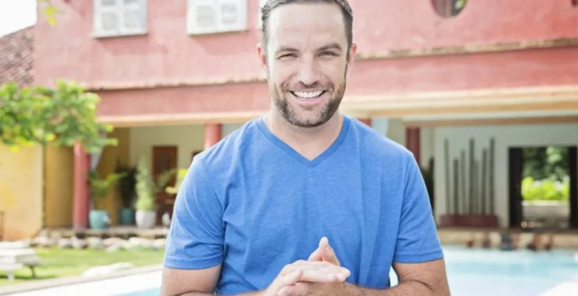 A man in a blue shirt smiles warmly at the camera