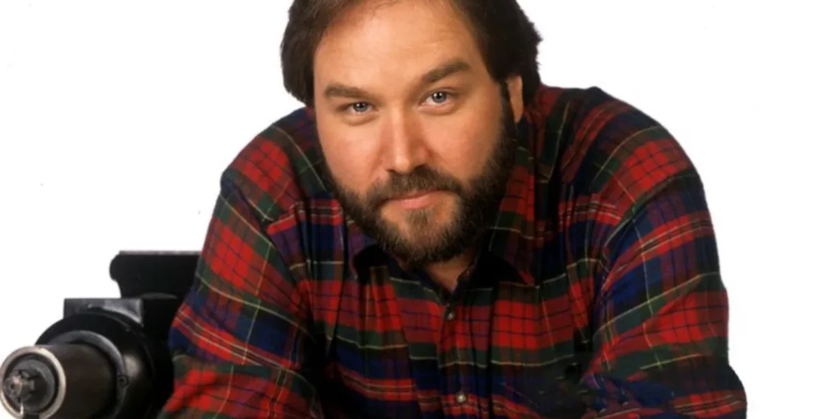A man with a beard wearing a red and black plaid shirt