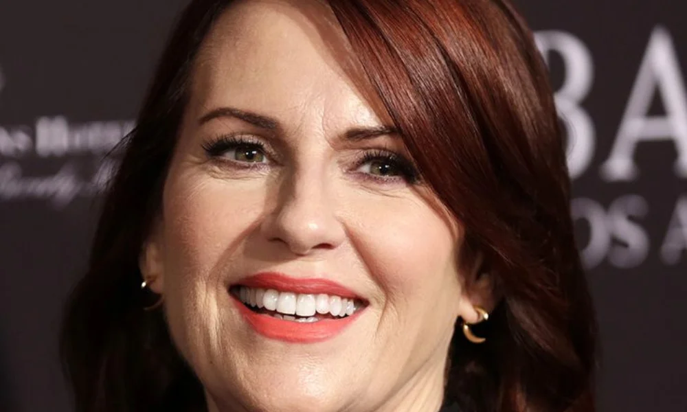 A person with red hair smiles warmly, showing-megan mullally net worth