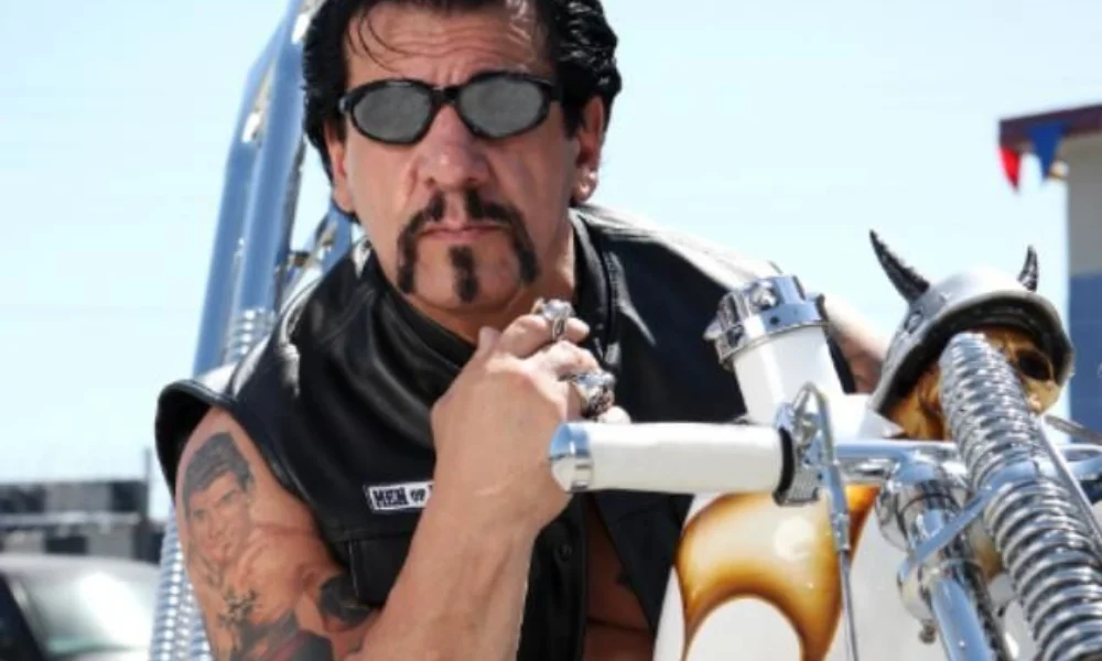 Man in sunglasses and leather vest posing confidently