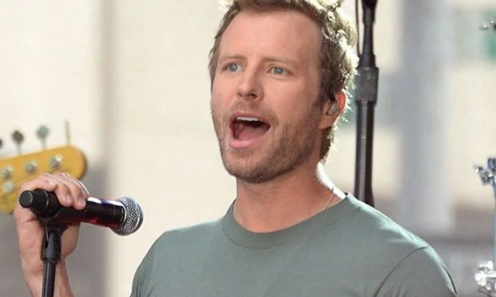 A man passionately sings into a microphone on stage-dierks bentley net worth