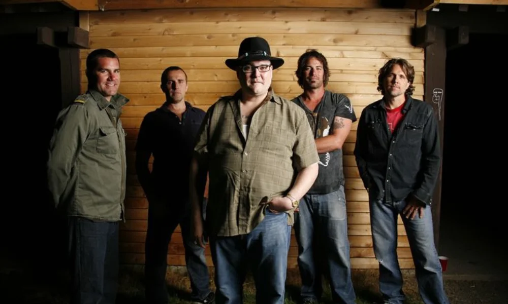A group of five men standing in front of a wooden cabin-john popper net worth