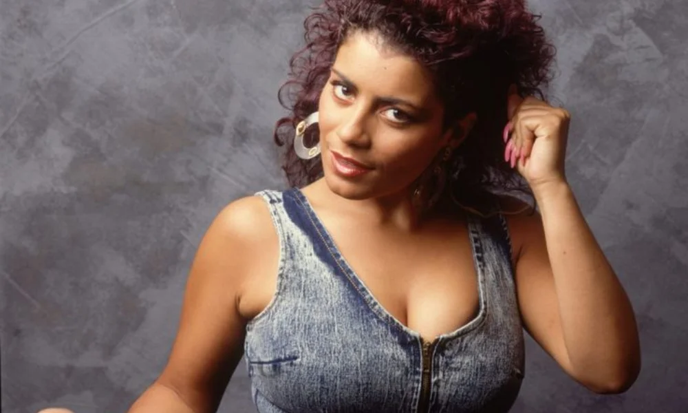 Woman with curly hair poses confidently-lisa velez net worth