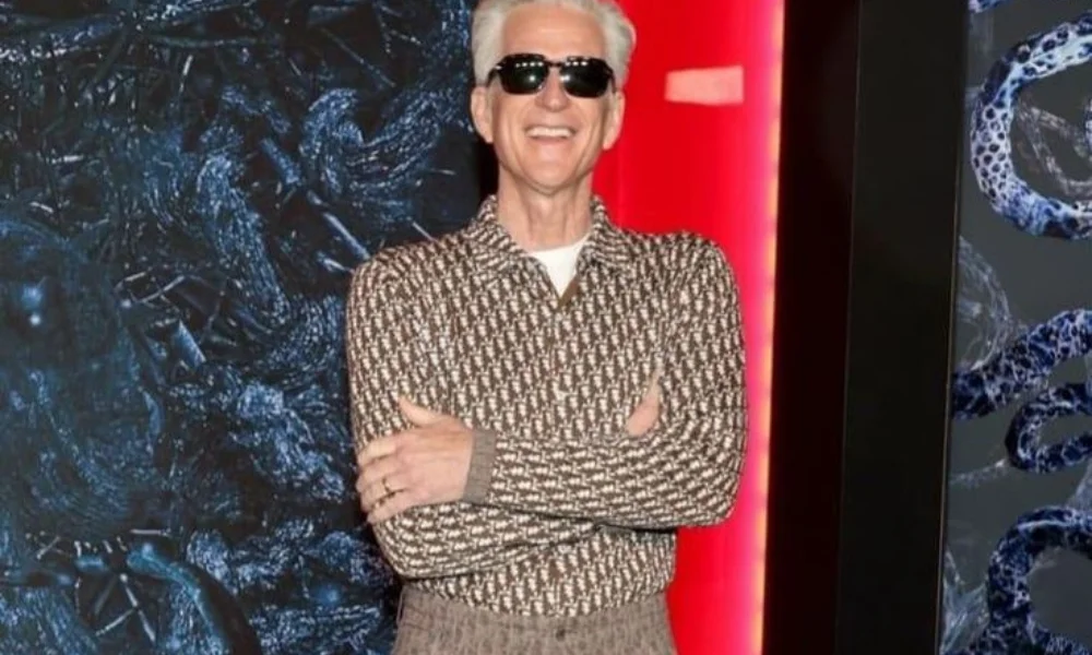 Smiling man with white hair and sunglasses wearing a patterned shirt-matthew modine net worth