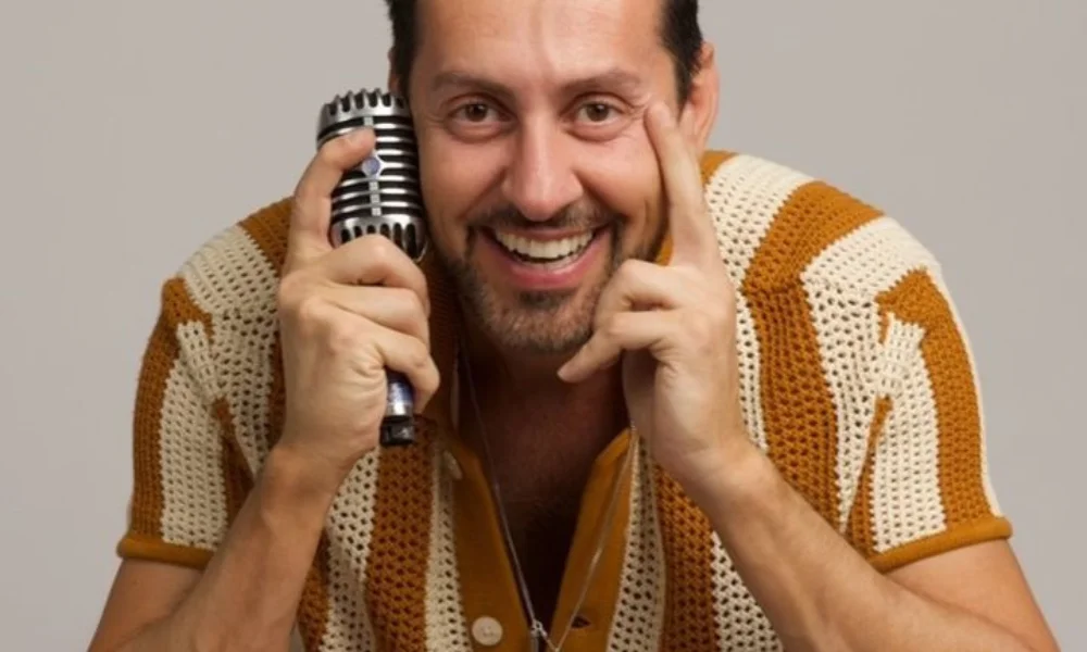 Smiling man in a vintage brown and cream crochet shirt-max amini net worth