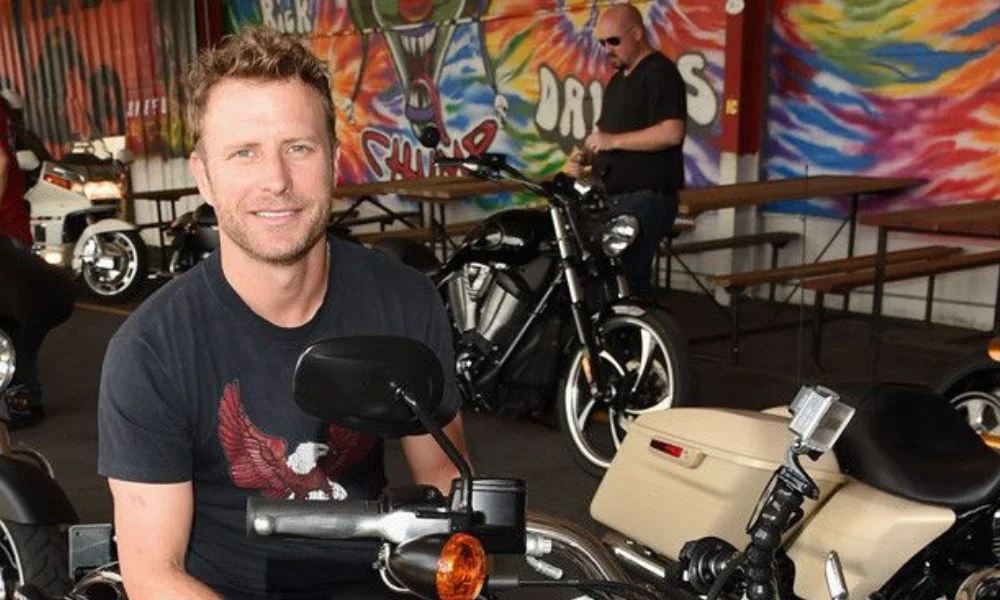 A smiling man sits casually on a motorcycle