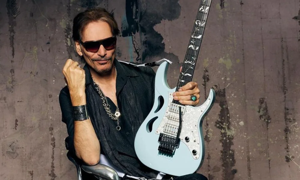 A man in sunglasses sits confidently-steve vai net worth