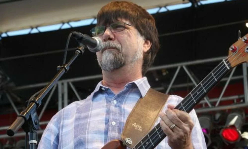 A man with a beard and glasses performs on stage