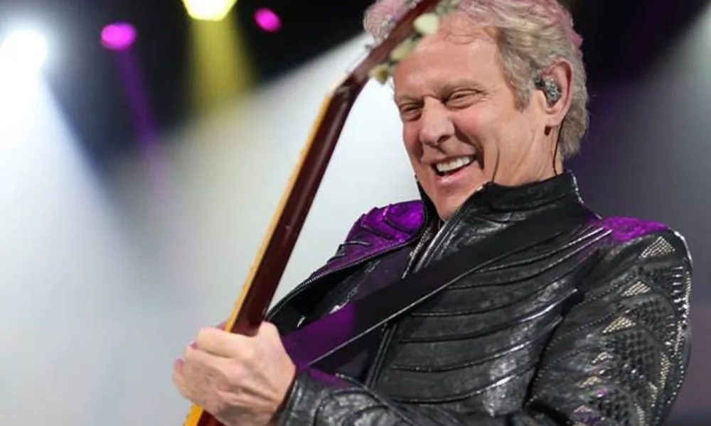 A guitarist in a black leather jacket plays passionately on stage-don felder net worth