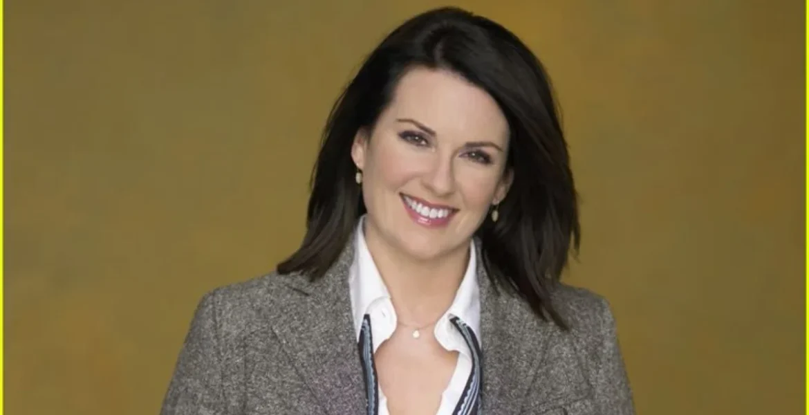 Smiling woman with dark hair wearing a gray blazer