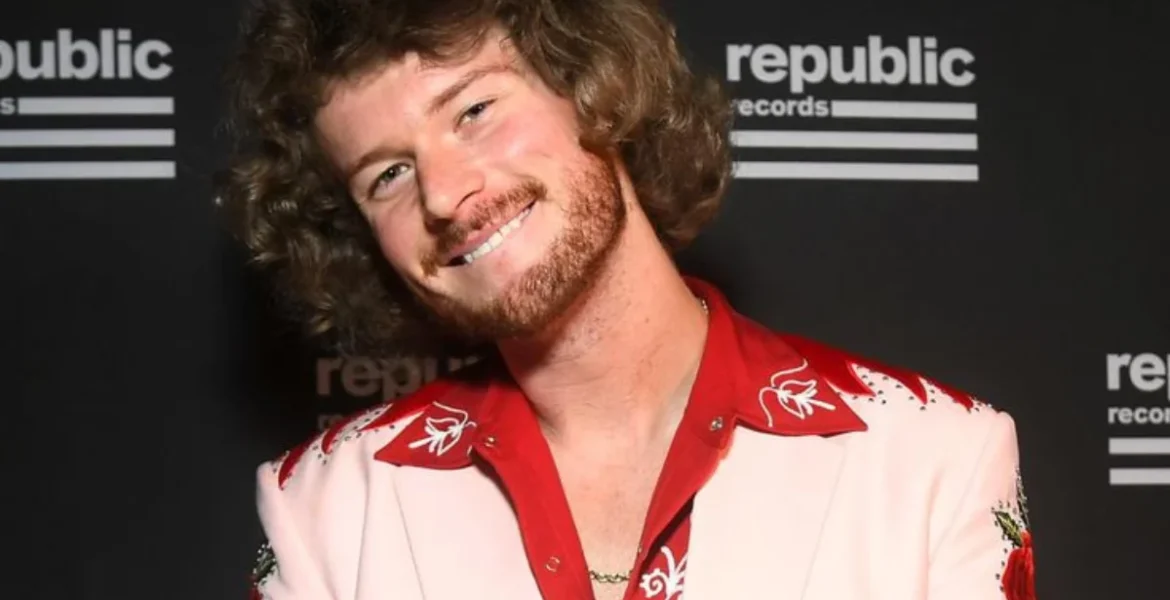 Smiling person with curly hair and a beard