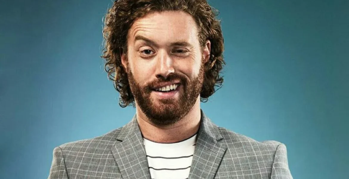 A bearded man in a gray plaid blazer